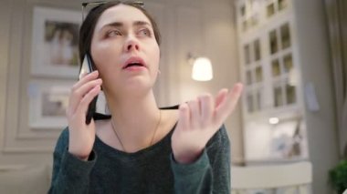 Cep telefonuyla konuşan gülümseyen genç bir kadının yakın plan portresi. Kapalı alanda. Gerçek zamanlı..