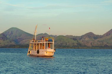 Okyanusta yüzen eğlence teknesi. Arka planda bir dağ zinciri var. Kapat..