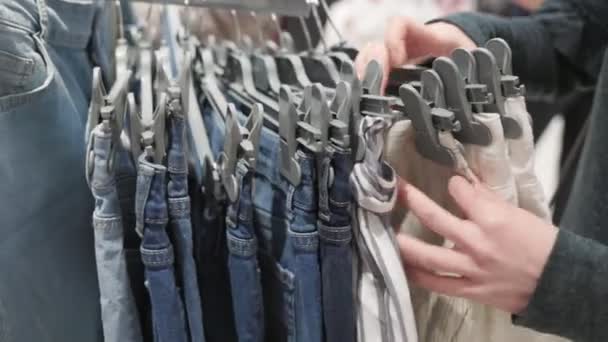 Dłonie Kobiety Bliska Przedzierają Się Przez Wieszaki Jeansowymi Spodenkami Wyjmują — Wideo stockowe