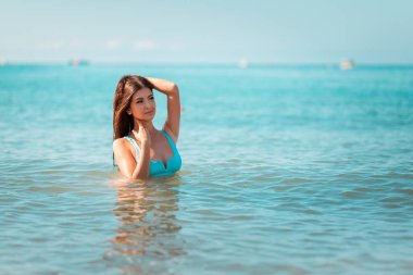Genç ve güzel bir kadın okyanusta yüzerken poz verir. Yaz tatili kavramı. Boşluğu kopyala.