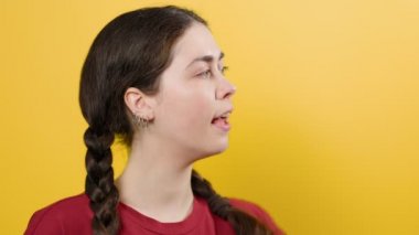 A pretty woman talking on a toy walkie-talkie made out of a paper cup. Yellow background. Communication concept.