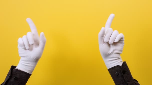 Mężczyzna Białych Rękawiczkach Wskazuje Palcem Wskazującym Zachowuje Się Żółtym Tle — Wideo stockowe
