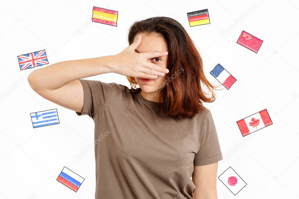English Language Day. Portrait of a woman covering her face with her hand. White background with flags of different countries. The concept of choosing to study foreign languages.