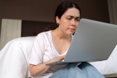 Laptoplara dikkatlice bakan genç bir kadının portresi. Çevrimiçi eğitim ve internet kursları kavramı.