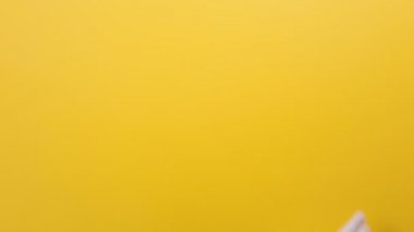 Beyaz eldivenli bir el hareketi seti. Baş parmaklar yukarı, zafer jesti, işaret etmek, telefon ekranındaki sayfayı krom anahtarla kaydırmak. Sarı arkaplan.