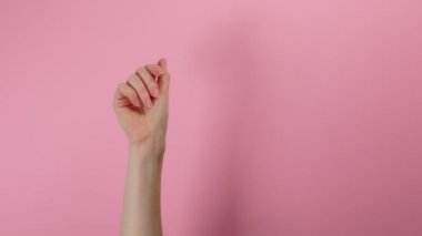 Bir kadının eli parasal bir jest gösterir. Pembe arkaplan.