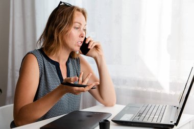 Uzaktan kumanda. Beyaz bir kadın evde grafik tabletle çalışıyor ve telefonda konuşuyor. Uzayı kopyala Karantina, serbest çalışma ve kendini izole etme kavramı..