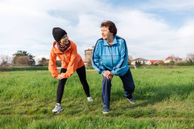 Mutlu Kafkasyalı büyükanne ve torun parkta birlikte spor yapıyor. Spor elbiseli yaşlı ve genç kadınlar ısınıyor. Uluslararası Yaşlılar Günü 'nde. Sağlıklı yaşam tarzı kavramı.