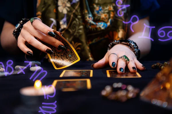 Fortune-telling on cards. A fortune teller lays out Tarot cards. Close up of hands. Zodiac circles are located in the corners of the image. The concept of divination, astrology and esotericism.