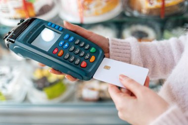 Bir kadın ödeme makinesine bir banka kartı yerleştiriyor. Eller yukarı. Üst Manzara. NFC konsepti, iş ve bankacılık operasyonları.