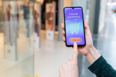 Bir kadının eli cep telefonu ekranını ve boş bir online mağaza arabasını gösteriyor. Kapatın. İnternet alışverişi kavramı.