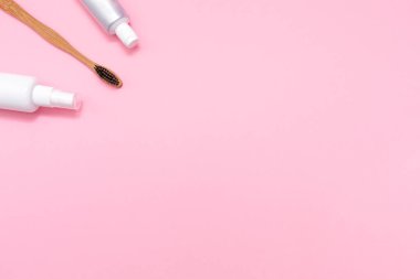 Eko ve hijyen. Bambu diş fırçası, ağız spreyi ve diş macunu. Düz yatıyordu. Pembe arka plan. Uzayı kopyala Çevre dostu hijyen araçları kavramı.