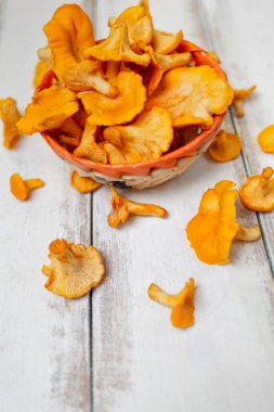 Turuncu mantarlar hasır sepetin içinde ve beyaz ahşap bir masaya saçılmış..