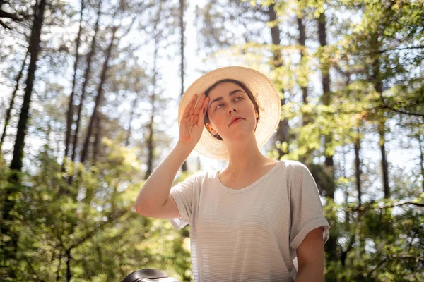 一个戴着草帽的年轻女子的画像 她擦着额头上的汗水 防止中暑的概念 — 图库照片