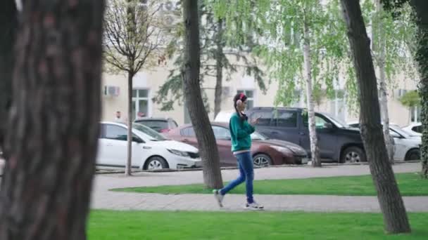 Een Jonge Vrouw Met Een Koptelefoon Loopt Door Straat Kiest — Stockvideo