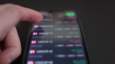 Borsa konsepti. İşadamı akıllı telefondan borsaya bakar. El ve akıllı telefon yakın çekim. Mobil ticaret uygulaması.