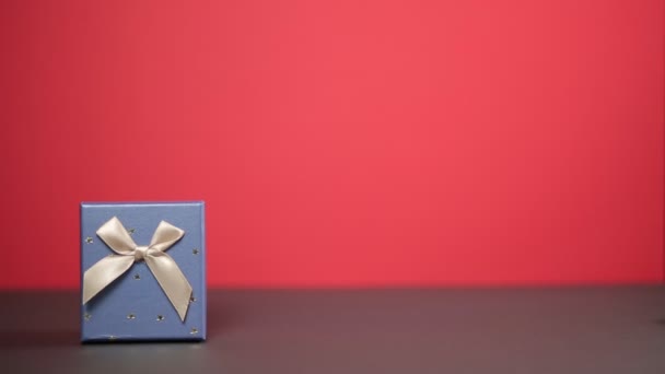 男の手は贈り物に向かって起伏する 赤の背景 クローズアップ 休日と贈り物の概念 — ストック動画