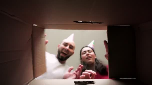 Kağıt Tatil Şapkalı Genç Bir Çift Bir Karton Kutuyu Açıyor — Stok video