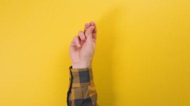 Adamın elini gömleğinin içine sokup parmağını şıklatıyor. Sarı arka plan. Reklam kavramı.