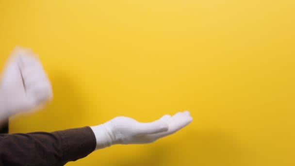 男士们的手戴着白手套玩石头剪子的游戏 表现出一种纸样的手势 黄色背景 — 图库视频影像