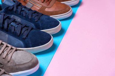 Yeni erkeğin arka arkaya dizilmiş renkli spor ayakkabıları. Ayakkabı uçları yakın plan. Pembe ve mavi arka plan. Yakın plan. Uzayı kopyala Shoemaker 'ın Tatil Konsepti.