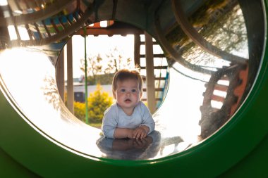 Çocuk parkında oynayan sevimli bir çocuk, tüpte sürünüyor. Açık havada. Mutlu Çocuk Günleri.