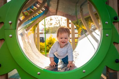 Çocuk parkında oynayan komik bir bebek, tüp içinde sürünüyor. Açık havada. Otizm kavramı.