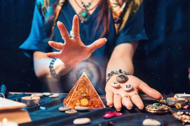 Astrology and magic. A fortune teller holds stones with the sign of the zodiac in her hands and conjures a magic pyramid. Close up. The concept of horoscopes and stories.