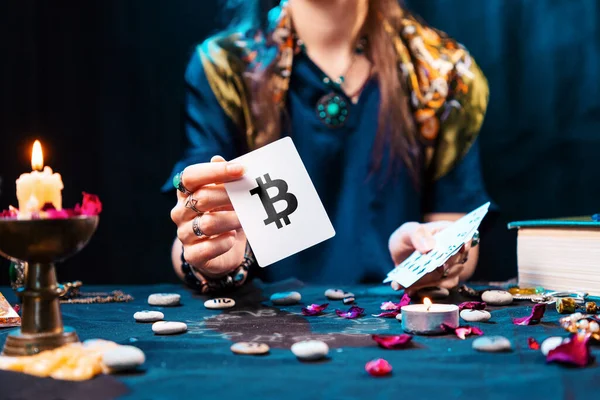 The fortune teller shows a card with the bitcoin currency. The concept of unpredictable cryptocurrency exchange trading.