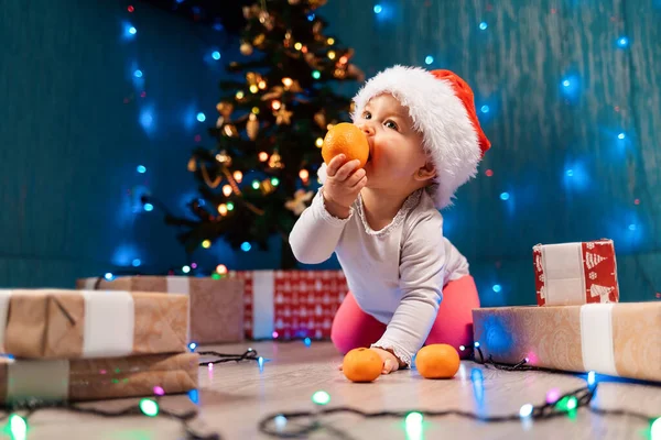 Caucasian Toddler Girl Xmas Hat Eating Tangerine Spruce Gifts Background — Foto Stock