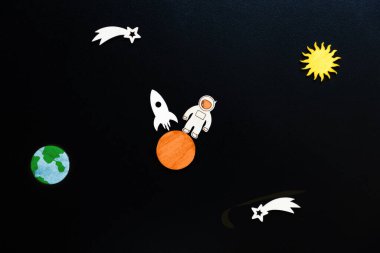 Mars 'ın kolonileşmesi. Astronot şeklinde ahşap uçaklar ve Mars 'a inen bir roket. Siyah arka plan, düz yatış. Uzay yolculuğu kavramı.
