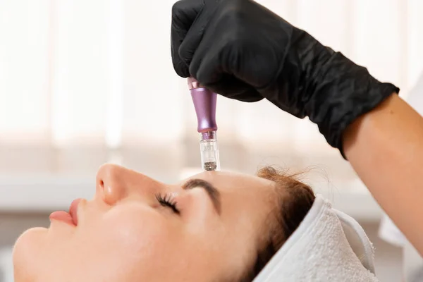 Salon kozmetolojisi. Lastik eldivenli güzellik uzmanı kadın yüzünün kısmi mezoterapi yöntemini uyguluyor. Alnını kapat. Profesyonel cilt bakımı kavramı.