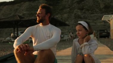 Yaz zamanı. Baba ve küçük kız sahilde oturup birbirleriyle konuşuyorlar. Yemek masası insanın yanında. Yavaş çekim.