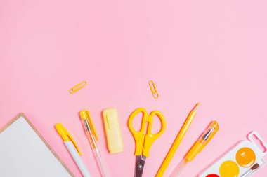 Okula dönelim. Pembe arka planda açık bir defter ve sarı ofis malzemesi olan kompozisyon. Düz yatıyordu. Uzayı kopyala Eğitim ve yaratıcılık kavramı.