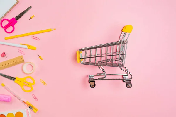 复制本 购物用品和黄色办公用品的组成为粉色背景 平躺在床上返回学校的概念和消费主义 — 图库照片