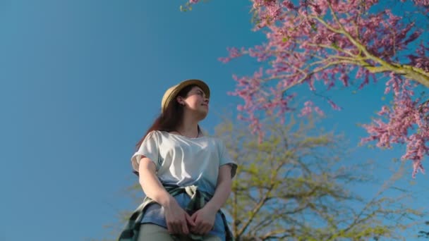 Eine Junge Frau Mit Strohhut Steht Unter Einem Sakura Baum — Stockvideo