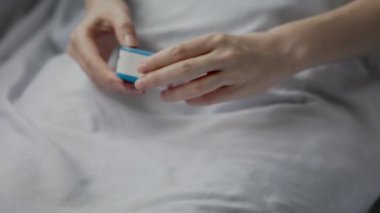 İşaret parmağında nabız oksimetresiyle yatakta yatan kadın. Elleri yakın çekim. Sağlık hizmetleri için malzemeler. Kandaki oksijen azmi kavramı.