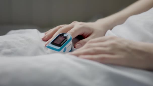 Vrouwelijke Handen Met Een Pulsoximeter Aan Wijsvinger Vrouw Bed Gadgets — Stockvideo