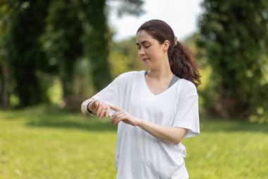 Genç gülümseyen kadının portresi akıllı saatini kontrol eder. Modern bir cihaz ve refah kavramı..