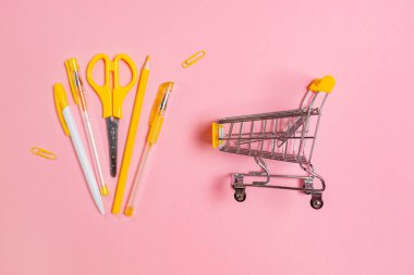 Pembe arka planda sarı ofis malzemesi olan oyuncak arabası. Düz yatıyordu. Okula ve alışverişe dönüş kavramı.