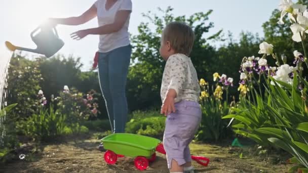 Czas Lato Cute Baby Girl Patrzeć Jej Matkę Podlewania Roślin — Wideo stockowe