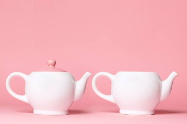 Pembe arka planda iki beyaz porselen çaydanlık. Uzayı kopyala Meme Kanseri Farkındalığı Ayı.