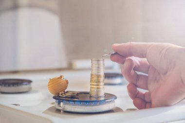 Yatırımcı kavramı ya da para biriktirme kavramı bir el şeklinde gaz ocağı ve küçük bir oyuncağın arka planına madeni para koyar..