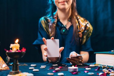 Büyü ve esotisizm konsepti. Gülen falcı boş bir beyaz tarot kartı gösteriyor. Haritacılık ve falcılık.