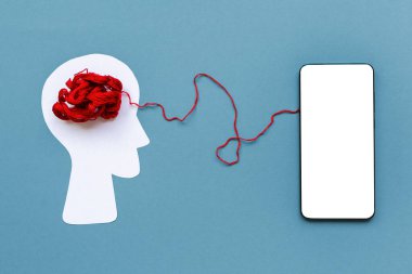 Dünya Alzheimer Günü. Kırmızı dolambaçlı insan kafasının kağıt silueti, akıllı telefonla mavi arka plan bağlantıları. Model yap. Düz yatıyordu. Ruh sağlığı kavramı.