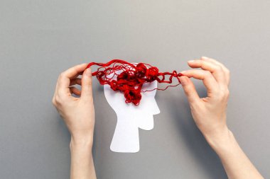 Kafanın siluetine dolanmış kırmızı iplikler, beyni temsil ediyor. Mavi arka plan. Düz yatıyordu. Akıl sağlığı ve bunama kavramı
