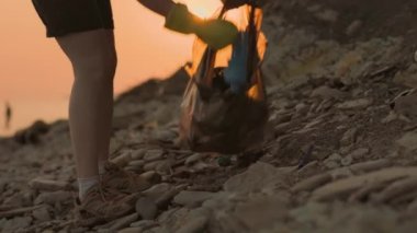 Dünya Günü. Lastik eldivenli bir kadın gönüllü, sahili çöpten temizliyor. Gerçek zamanlı. Çevre koruma kavramı