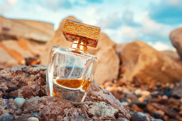 Çakıl Taşlı Plajda Altın Şeffaf Bir Parfüm Şişesi Arka Planda — Stok fotoğraf