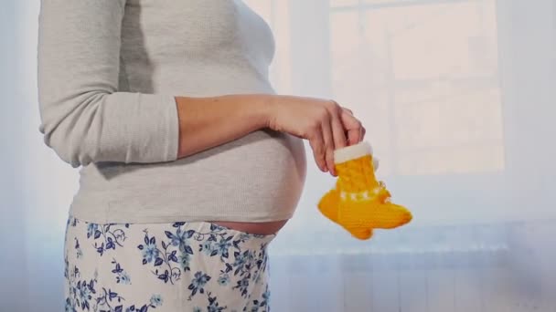Mladá Těhotná Žena Stojí Okna Mává Pletenými Botami Pokládá Dlaň — Stock video