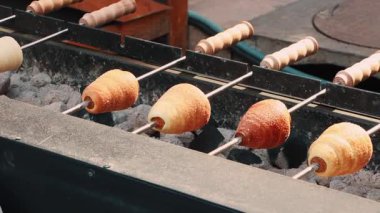 Kapalı katmanlı kruvasanların sokak yiyecek pazarındaki açık kömür ızgaralarında kızartılarak altın kıtır dokusunu ve fast food konseptinde lezzetli pişirme sürecini göstermeleri.